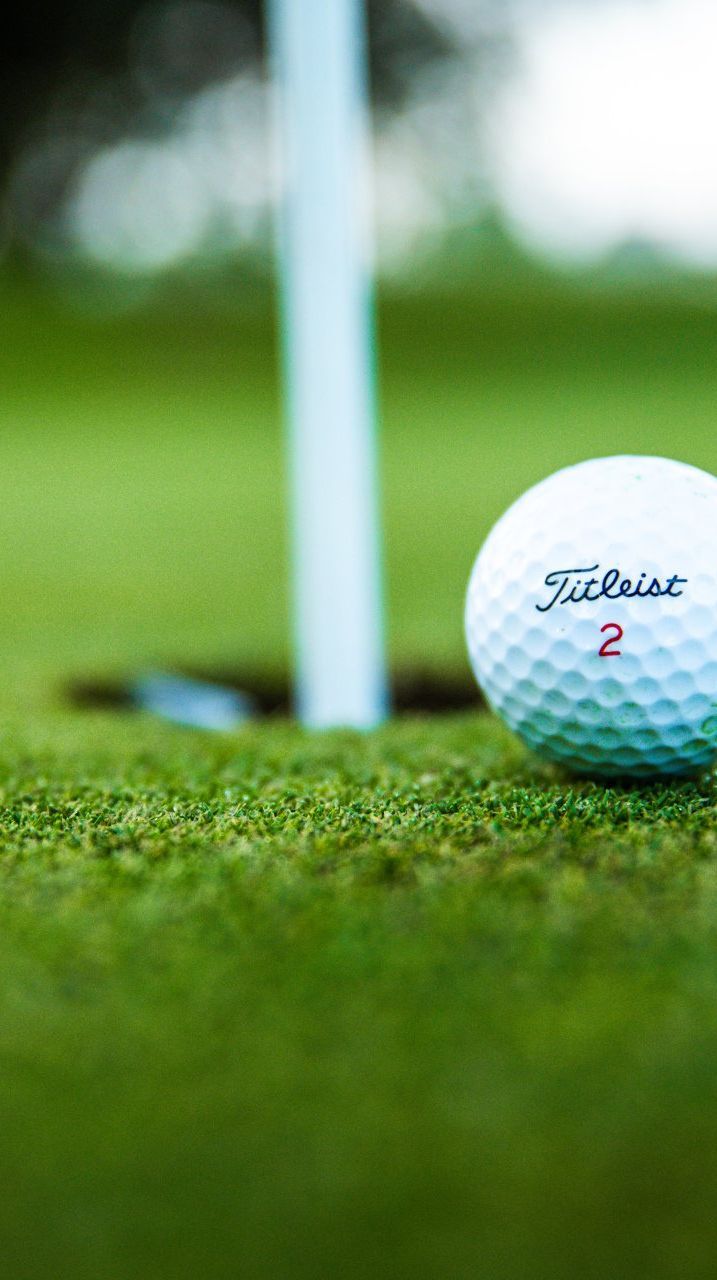 A golf ball is sitting on top of a green next to a hole.