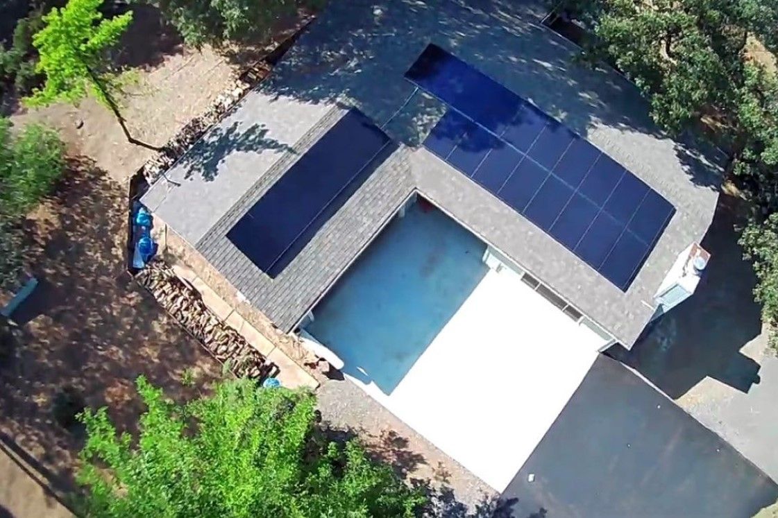 An aerial view of a house with a pool and solar panels on the roof.