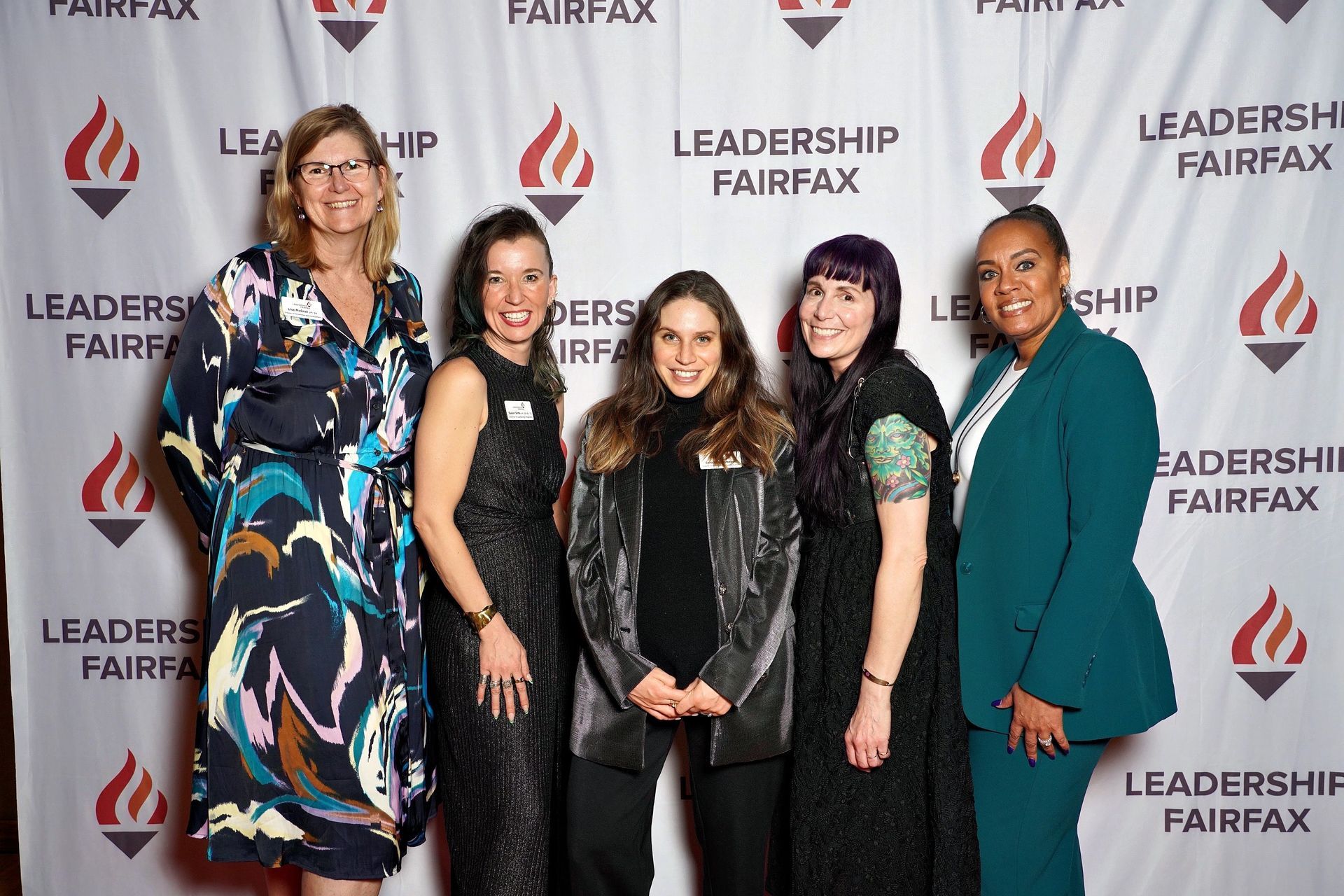 a group of women are posing for a picture in front of a backdrop .