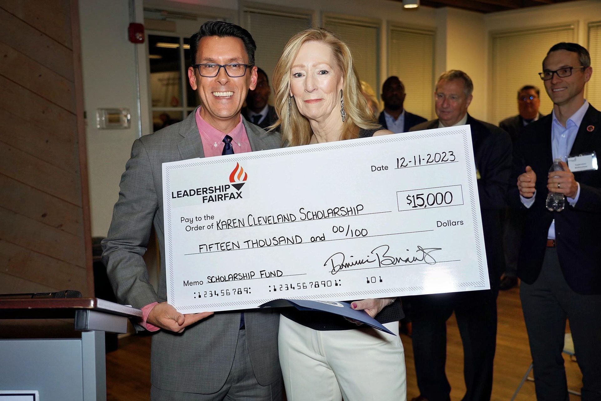 a man and a woman are holding a large check