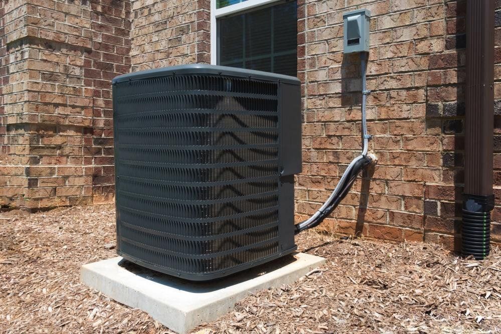 An air conditioner is sitting outside of a brick building.