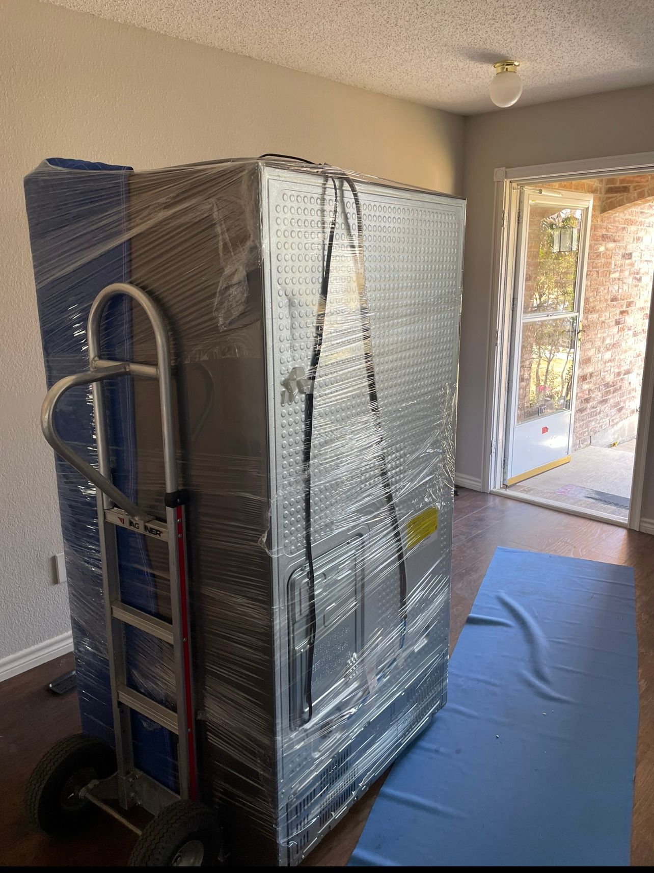 a man in a blue shirt is wrapping a piece of furniture in plastic wrap