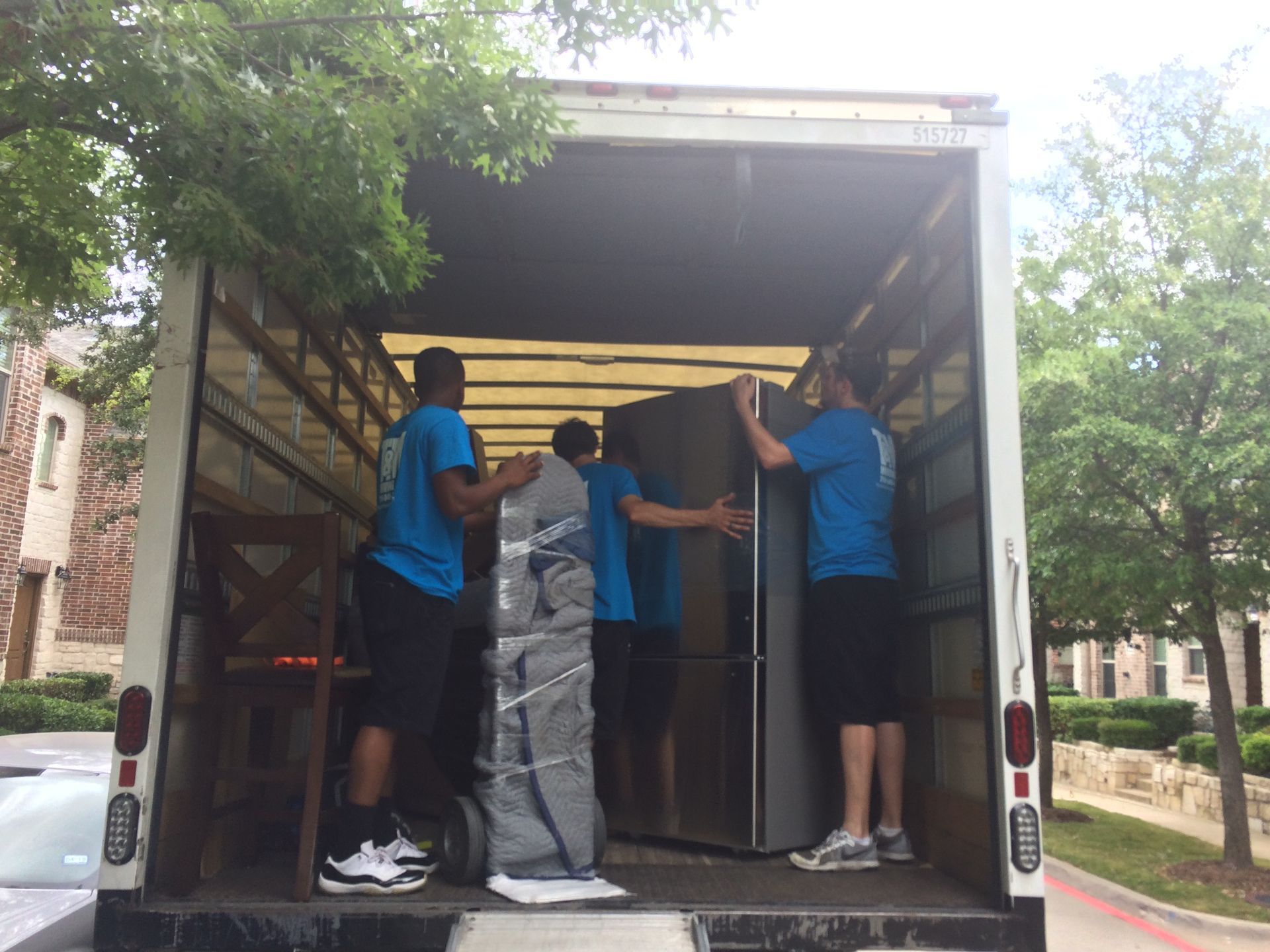 a man in a blue shirt is wrapping a piece of furniture in plastic wrap