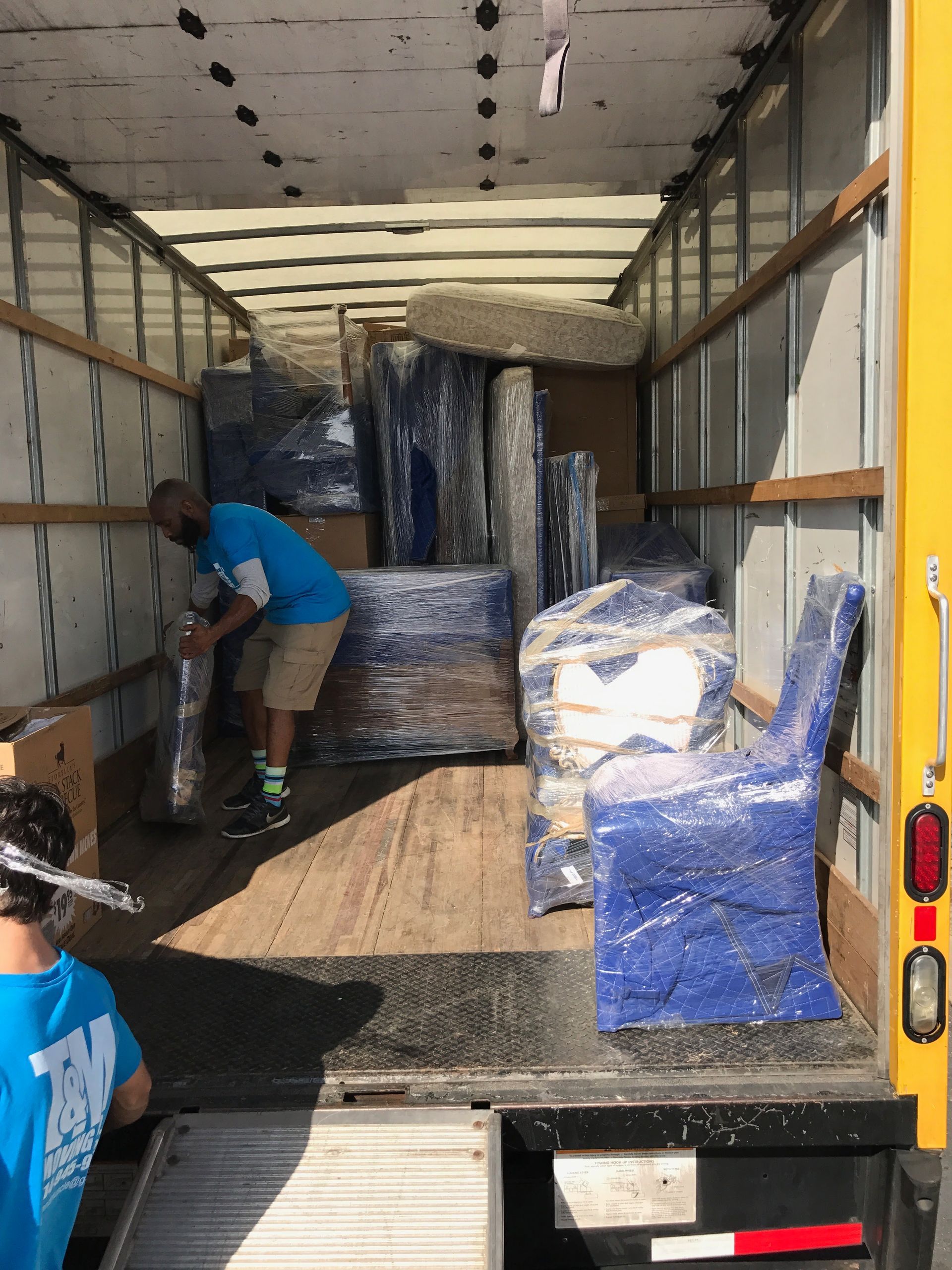 a man in a blue shirt is wrapping a piece of furniture in plastic wrap