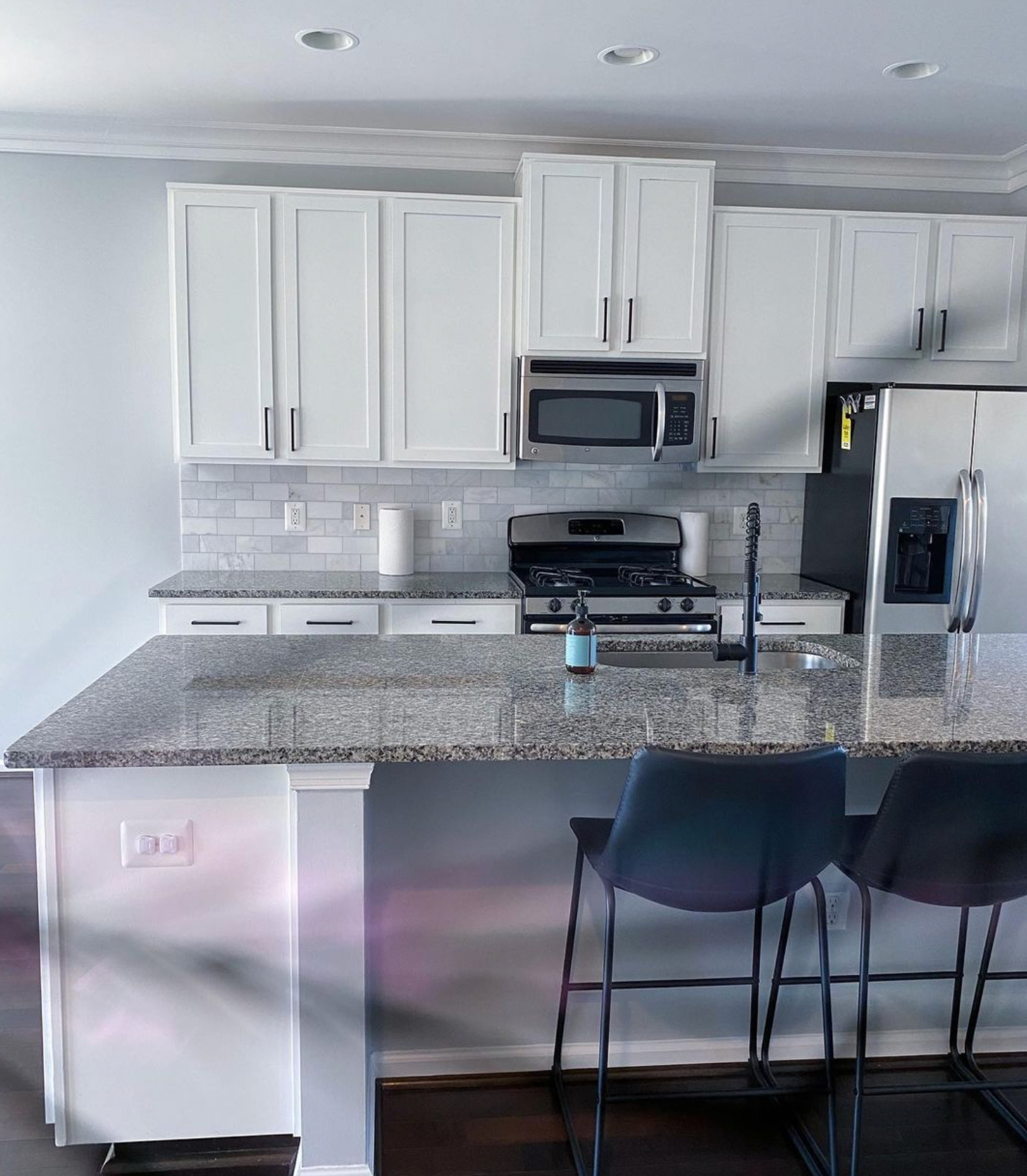 A kitchen with granite counter tops and white cabinets