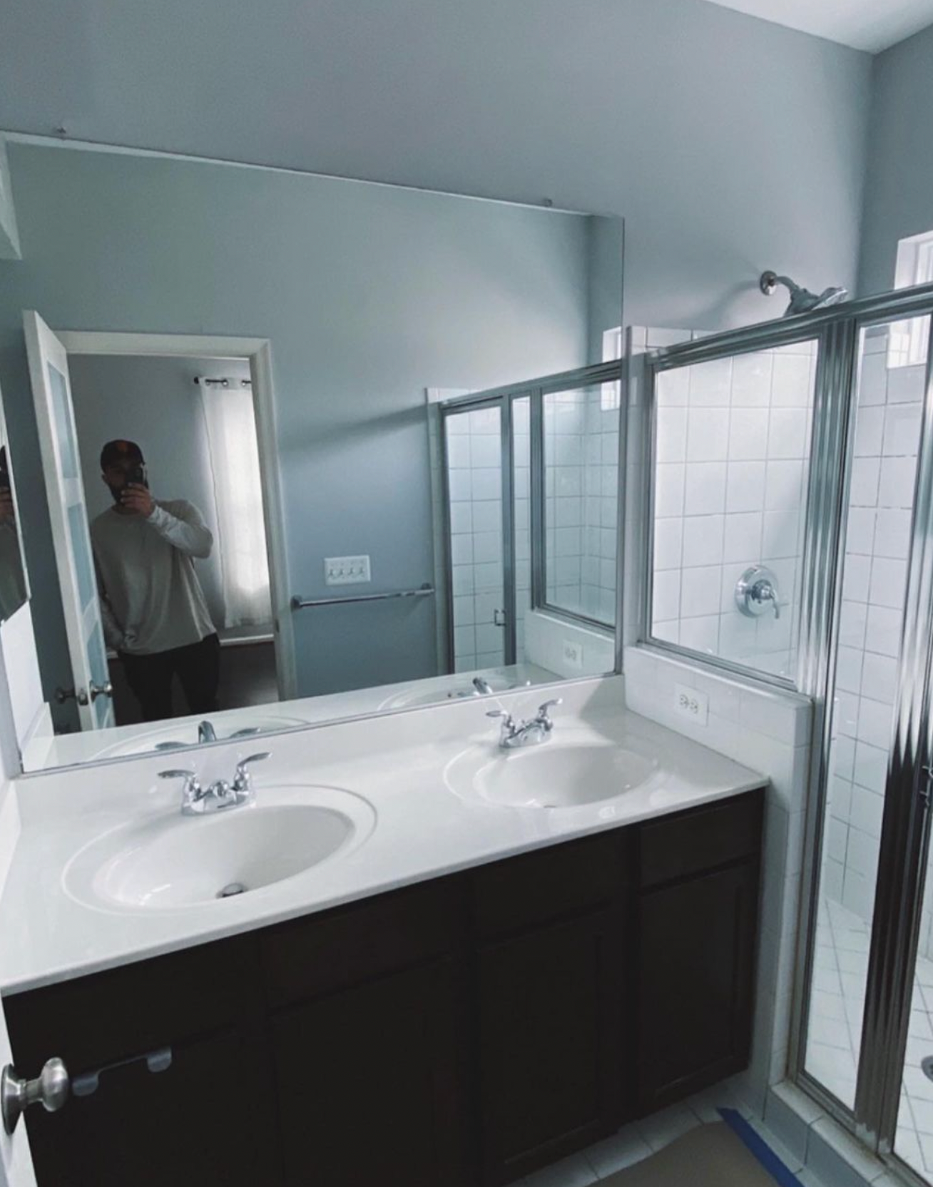 A bathroom with two sinks and a large mirror very basic condo low cost.