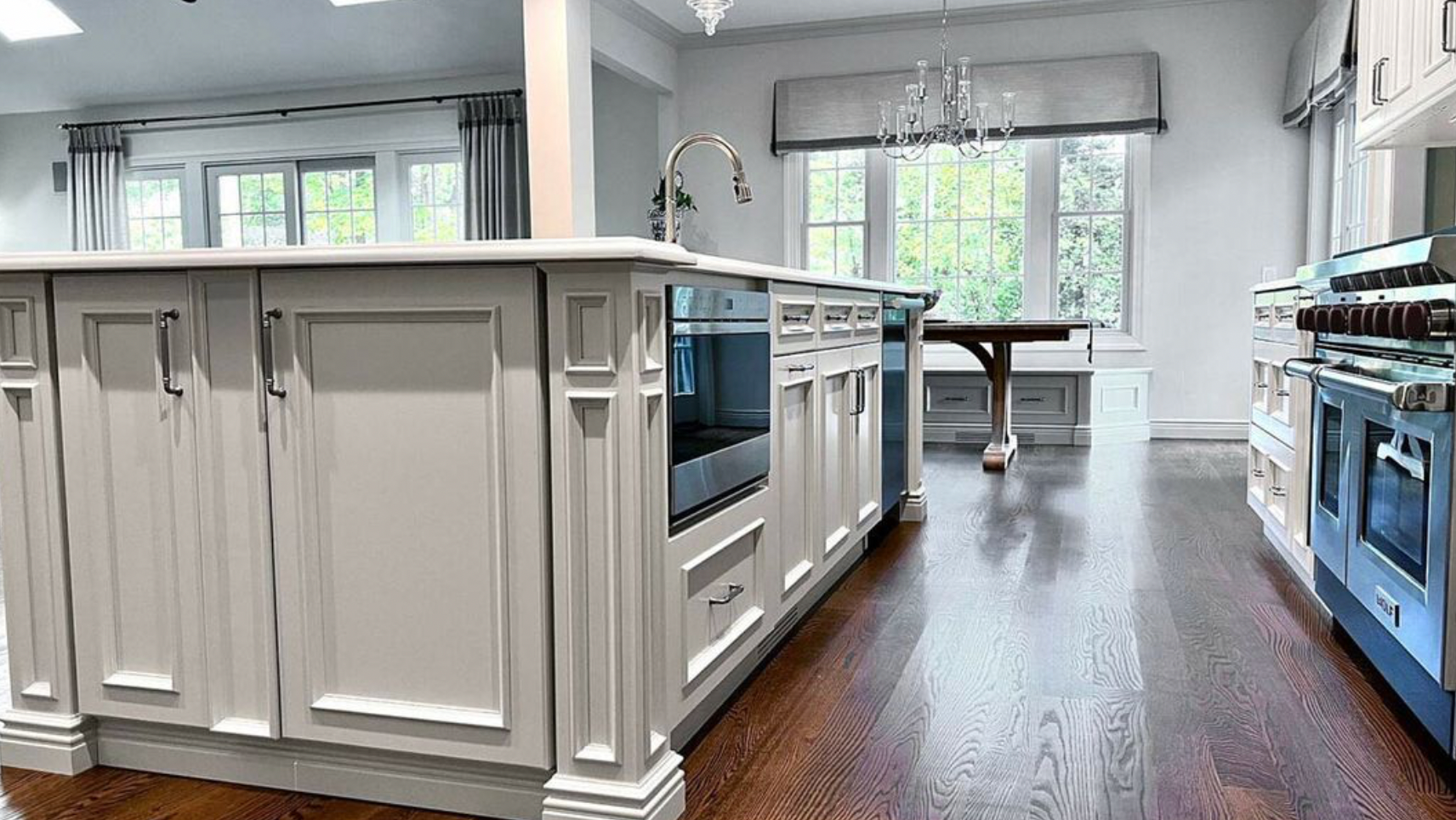 A kitchen with white cabinets and blue appliances and a large island in the middle.