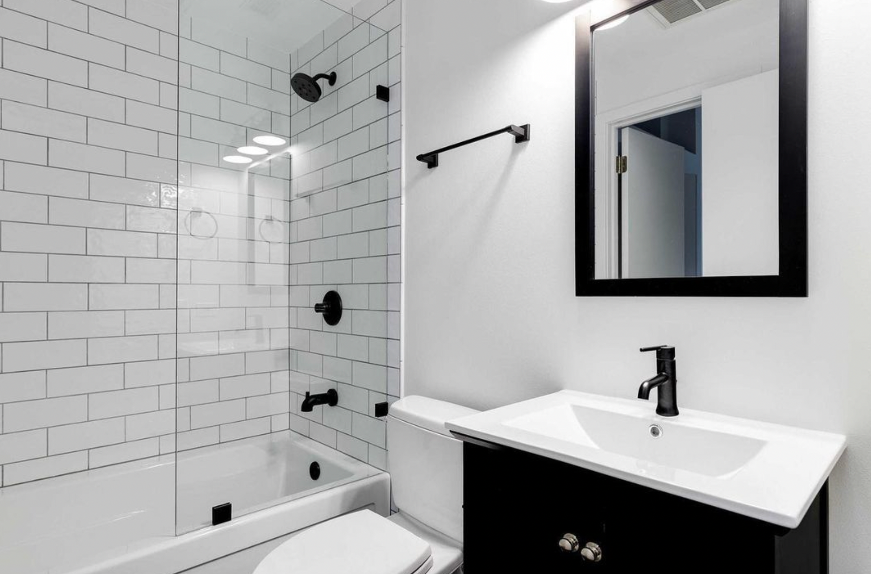 A bathroom with a toilet , sink , shower and mirror.
