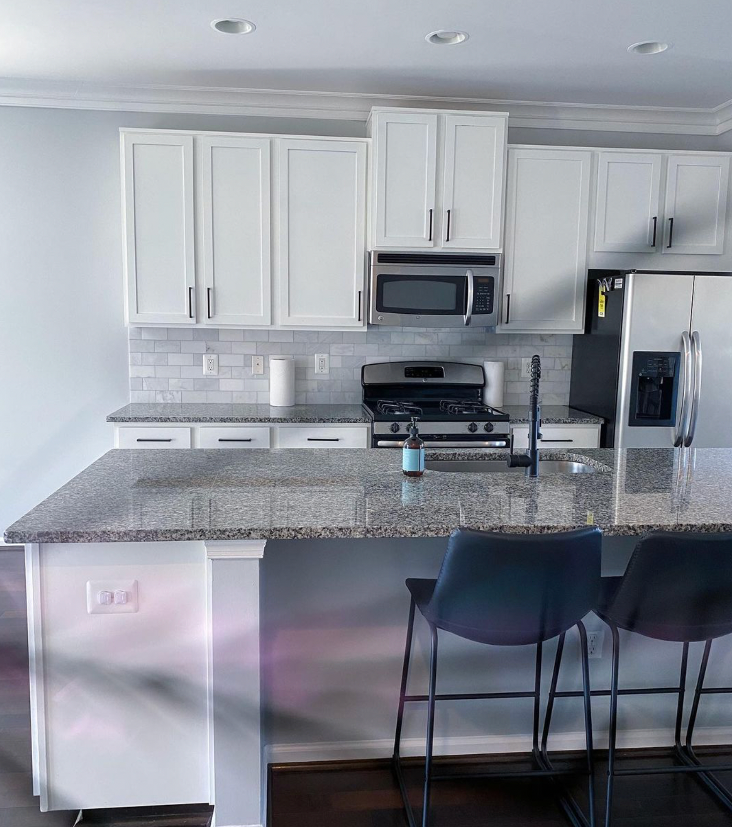 A kitchen with granite counter tops and white cabinets