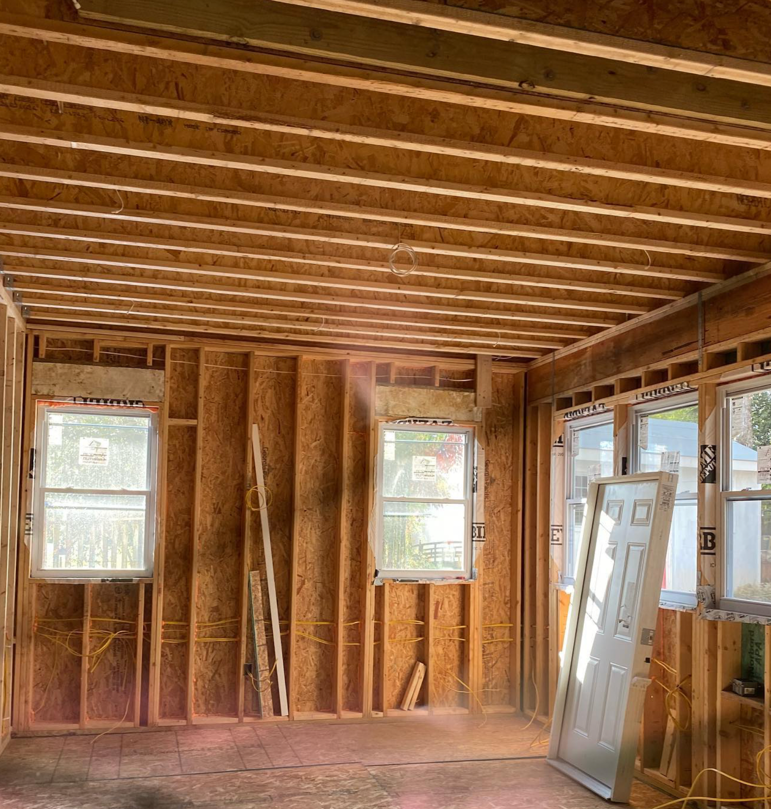 A room in a house under construction with a door and windows