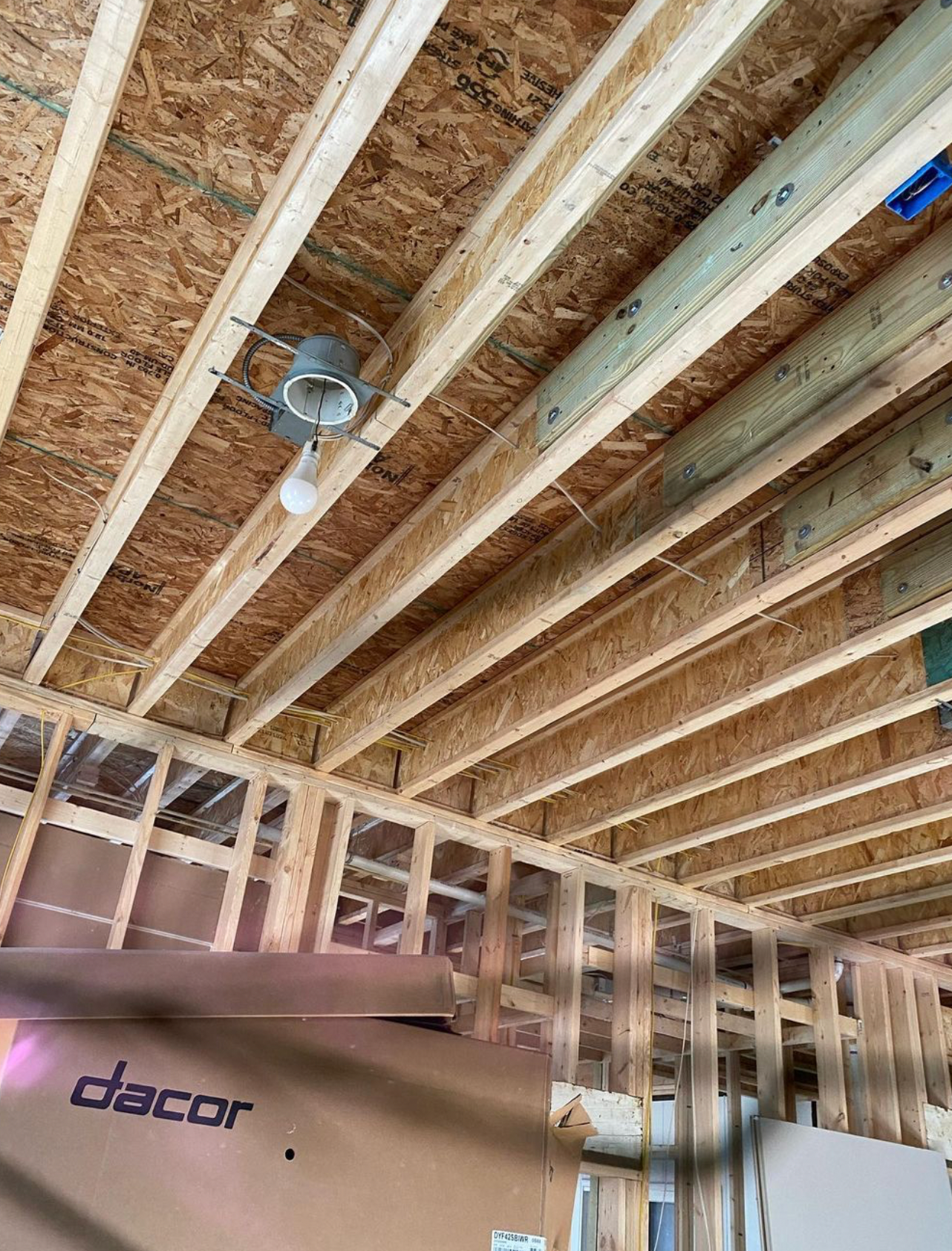 A ceiling fan is hanging from the ceiling of a house under construction.
