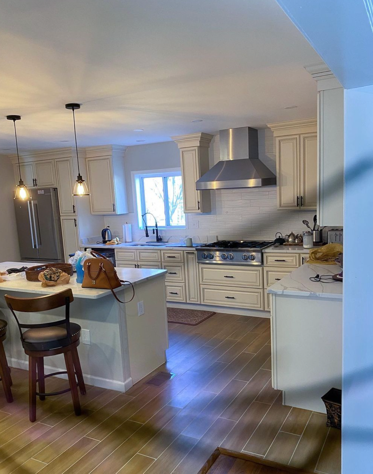 A kitchen with white cabinets , stainless steel appliances , a stove and a refrigerator.