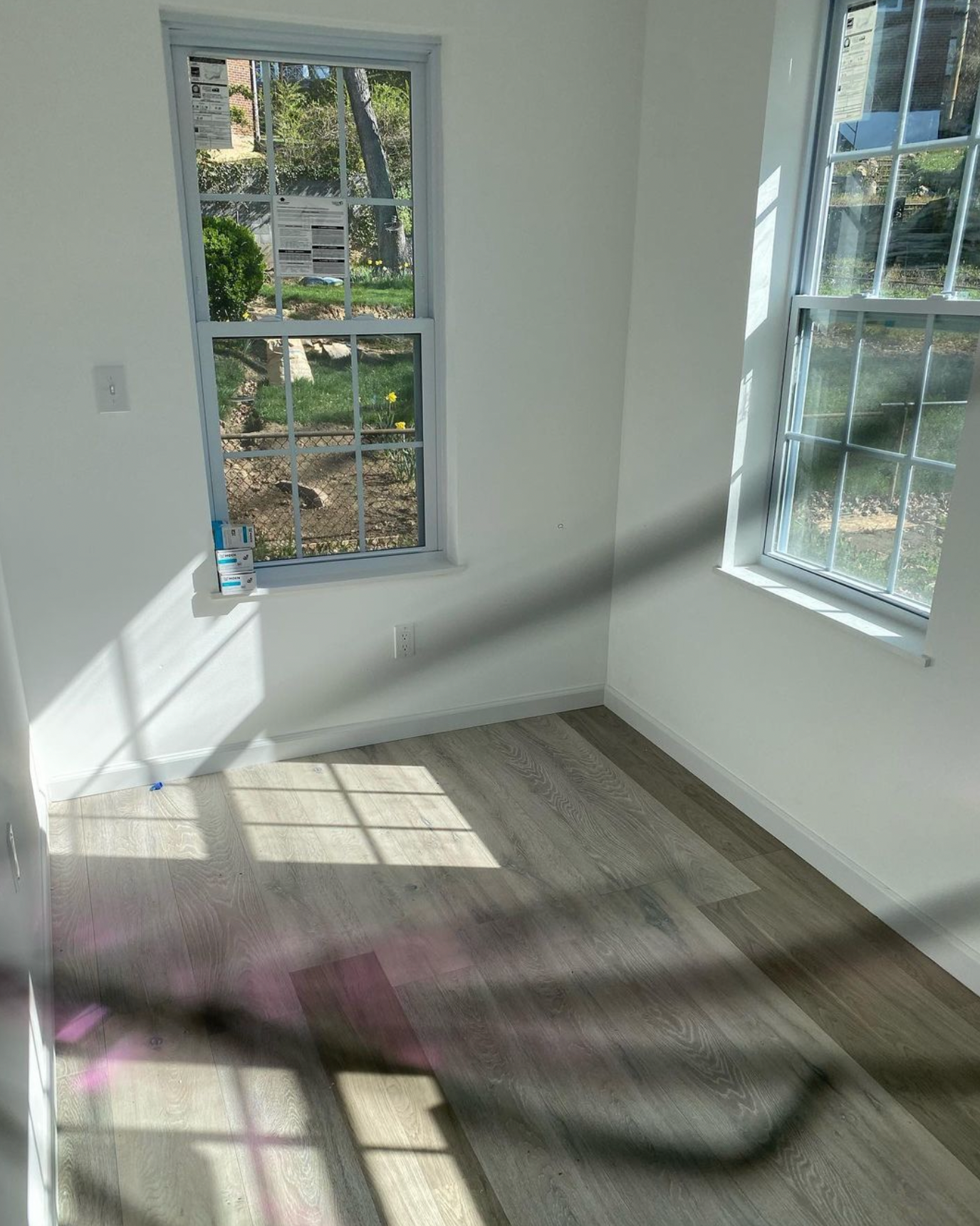 A room with two windows and a rug on the floor, finished small addition.