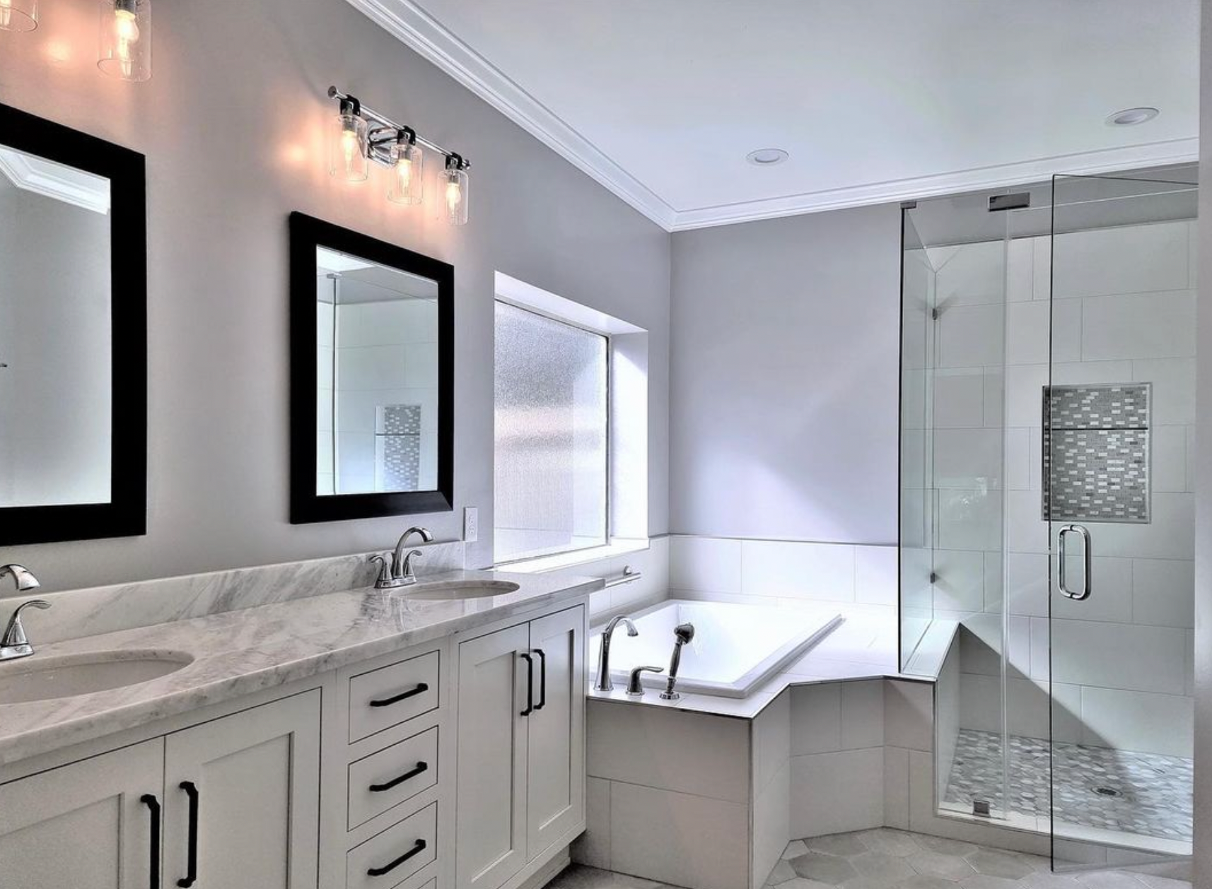 A bathroom with two sinks , a tub , and a walk in shower.