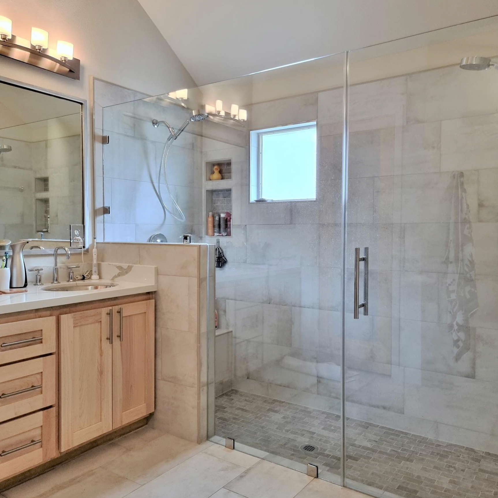 A bathroom with a walk in shower and a sink
