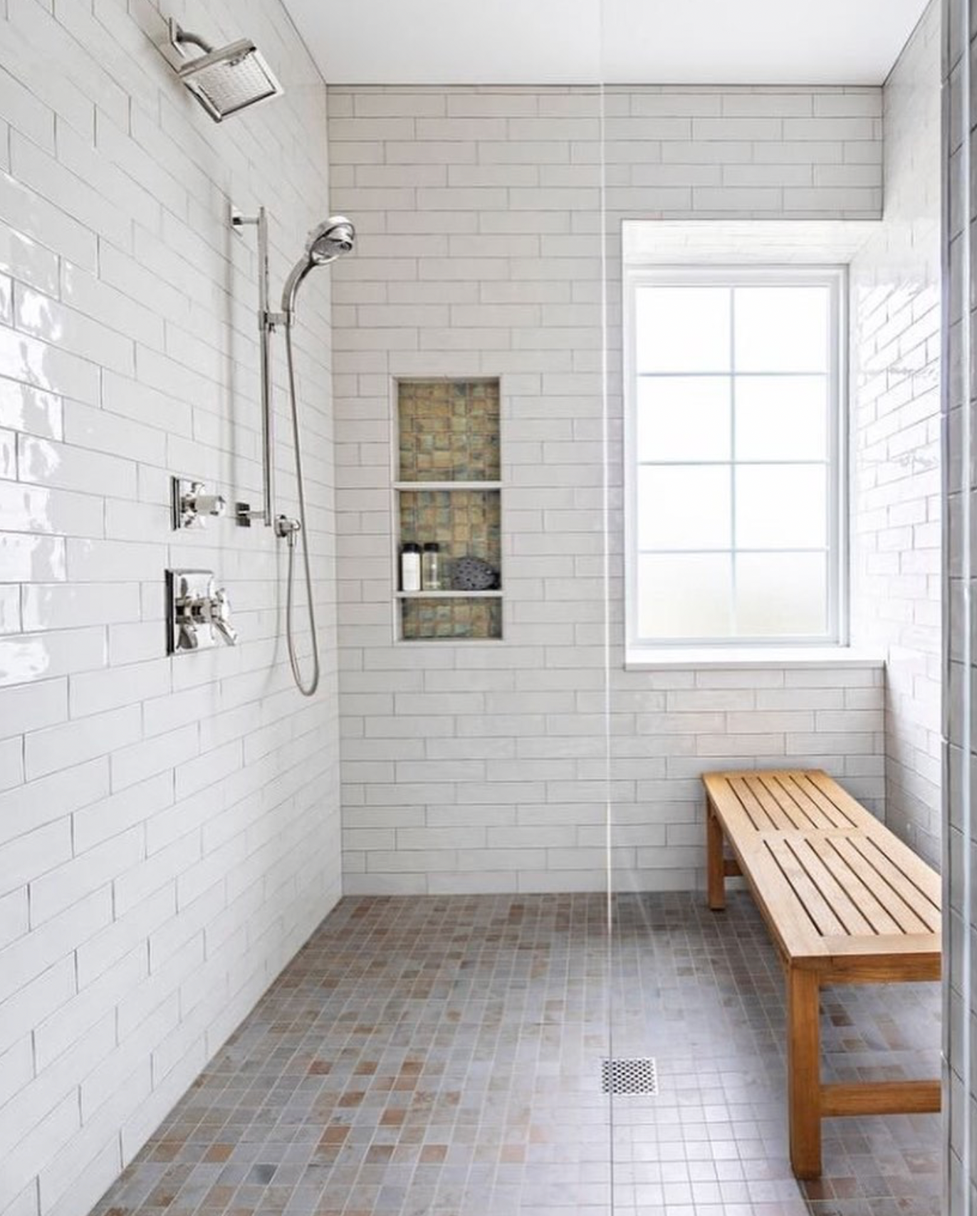 A bathroom with a walk in shower and a wooden bench.