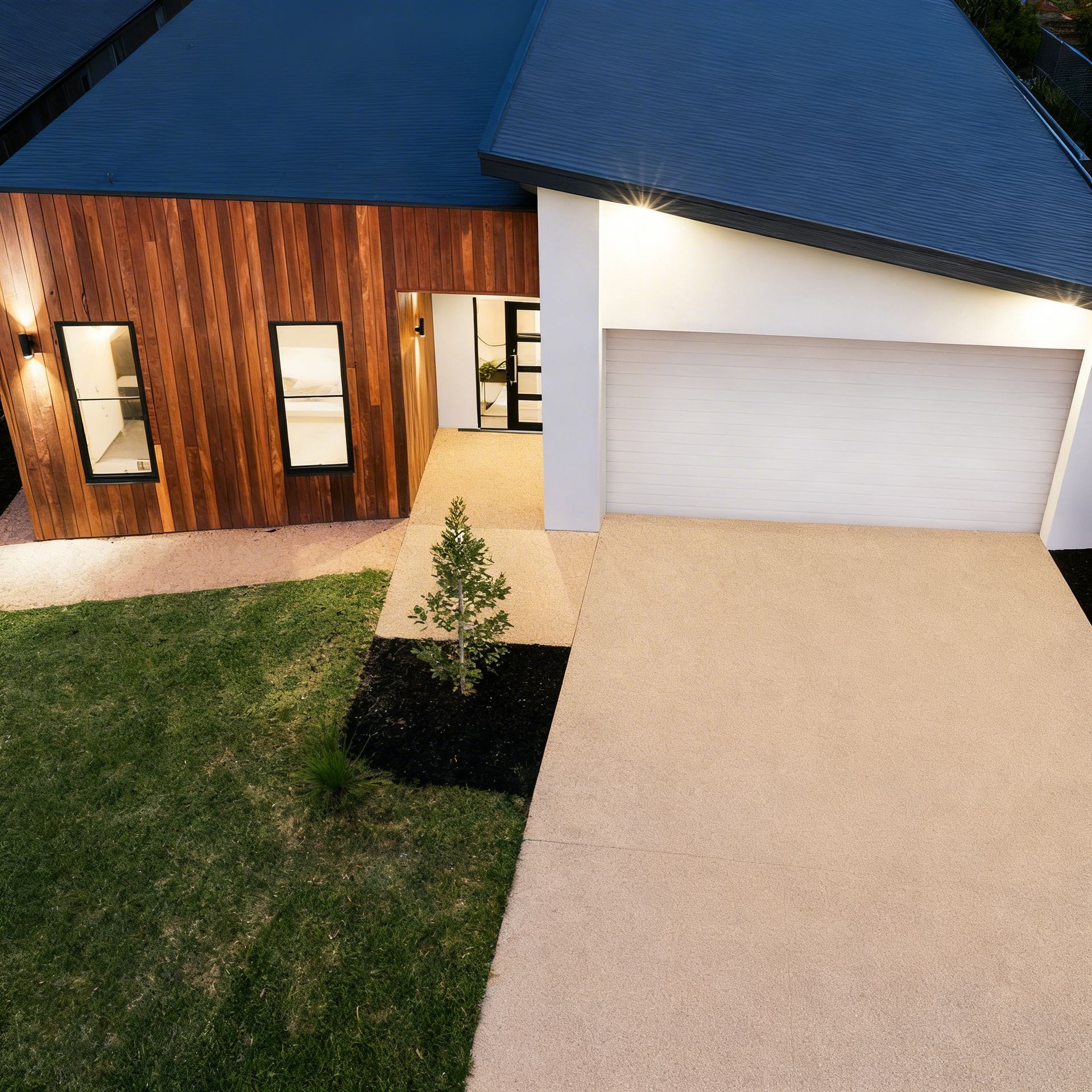 Modern home exterior with wooden siding, white garage, and paved driveway.