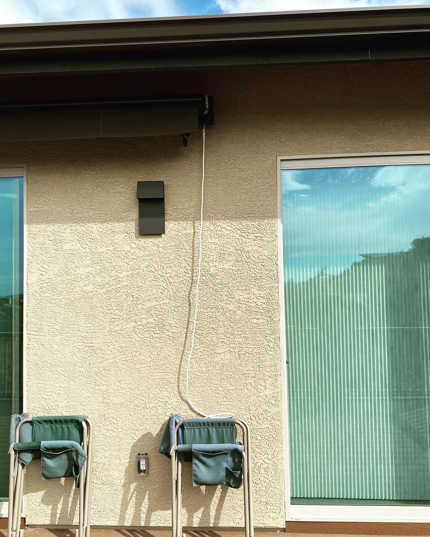 A house with a sliding glass door and two chairs in front of it