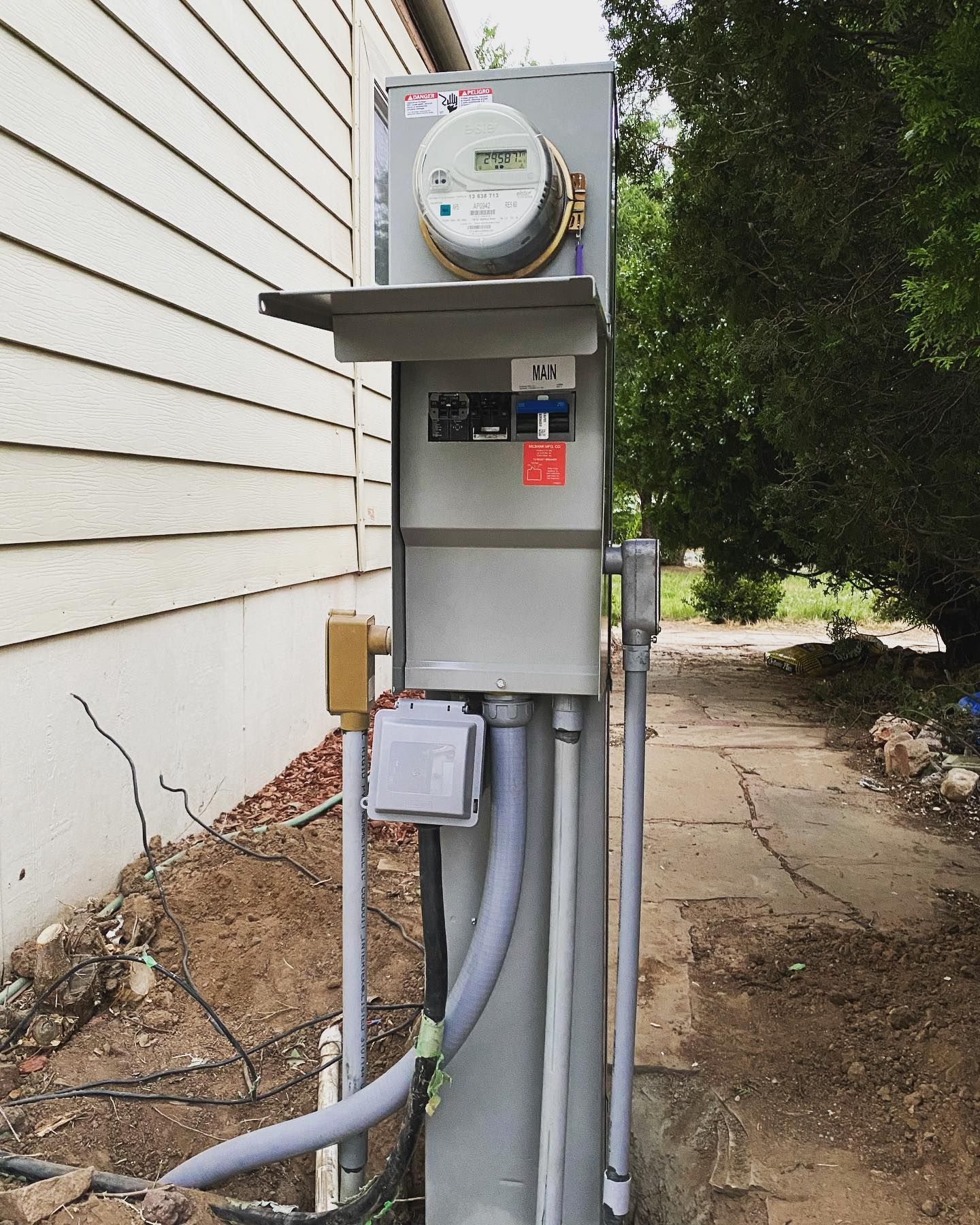 A meter is sitting on top of a pole next to a house.