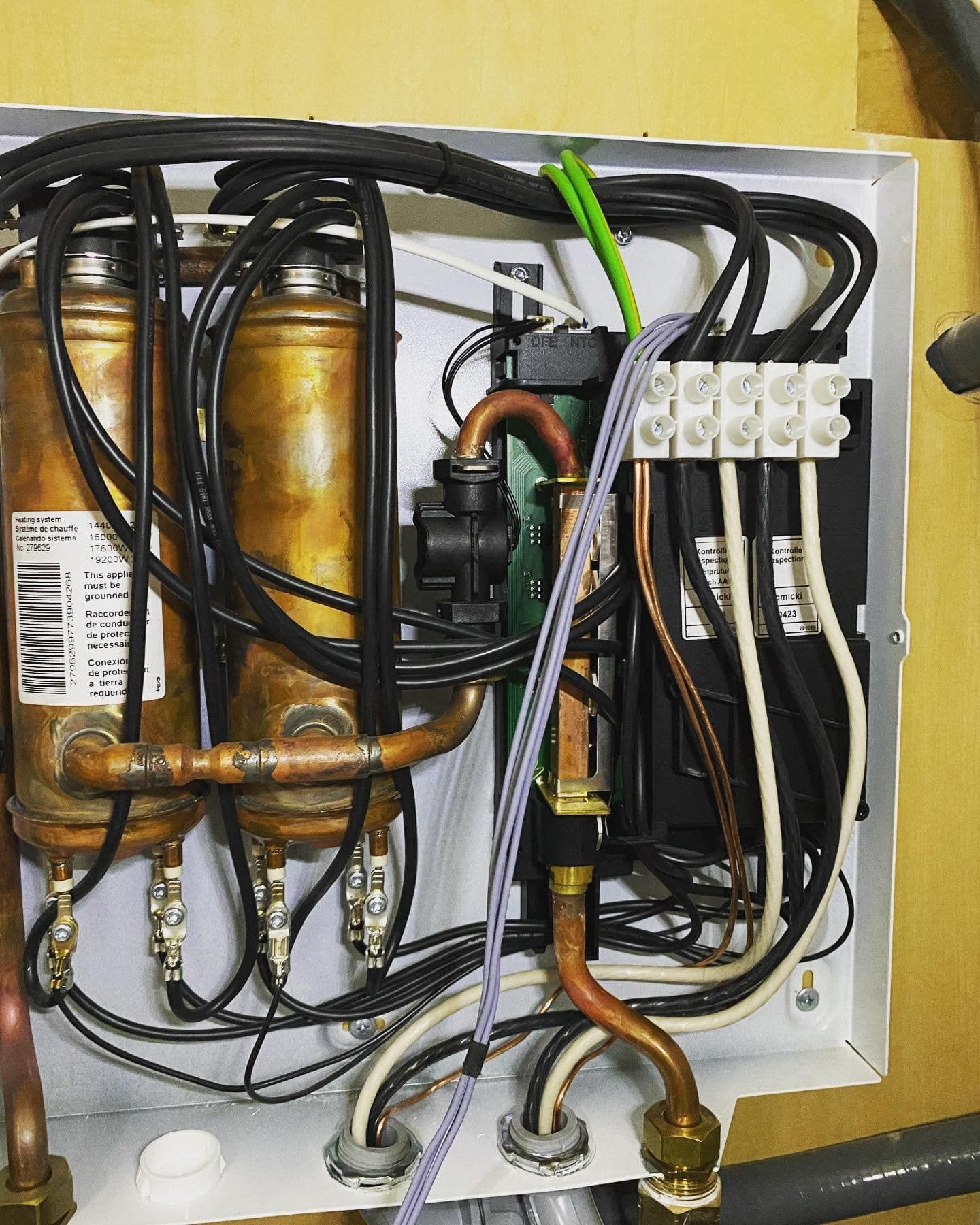 The inside of a box with copper pipes and wires