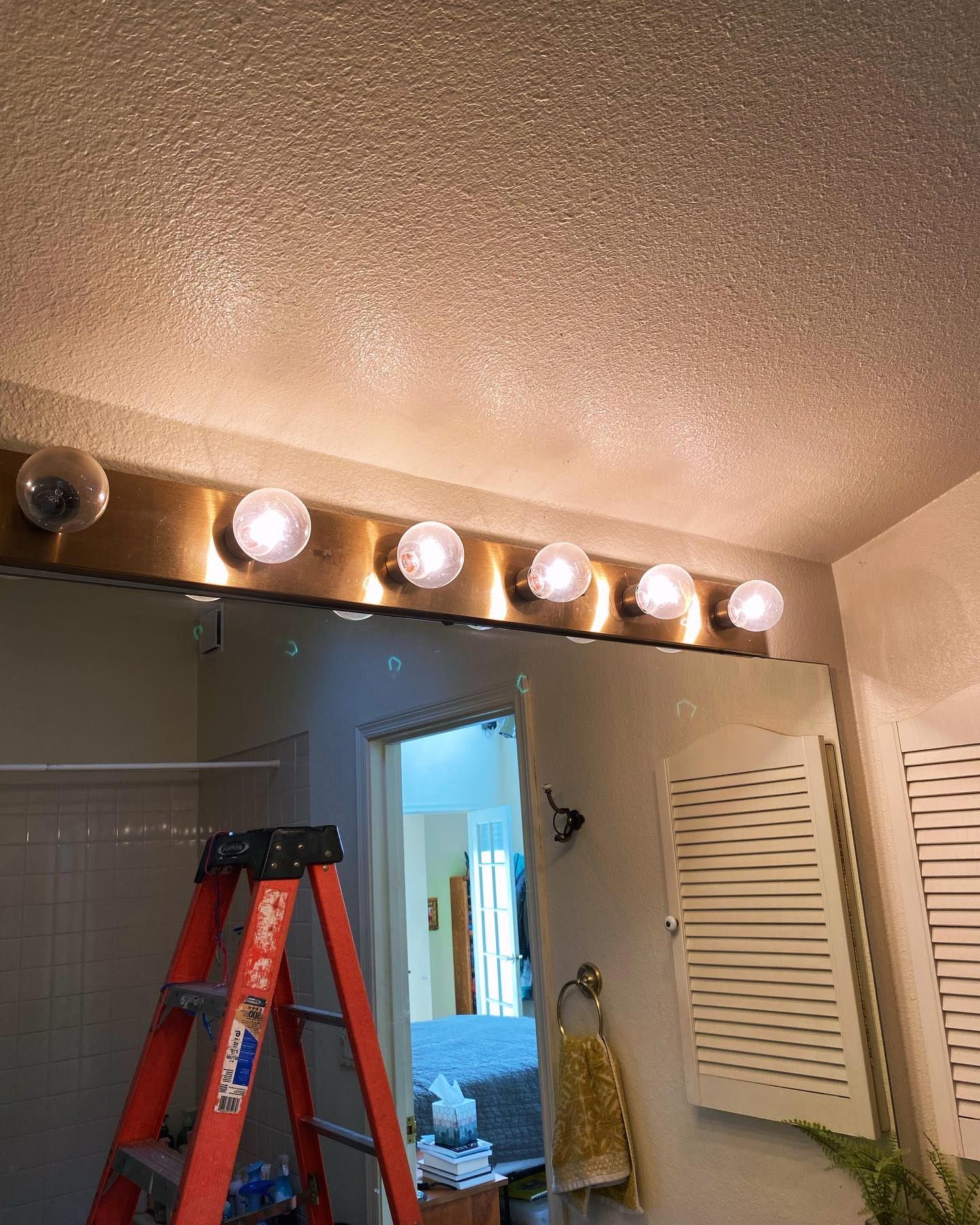 A bathroom with a ladder in front of a mirror.