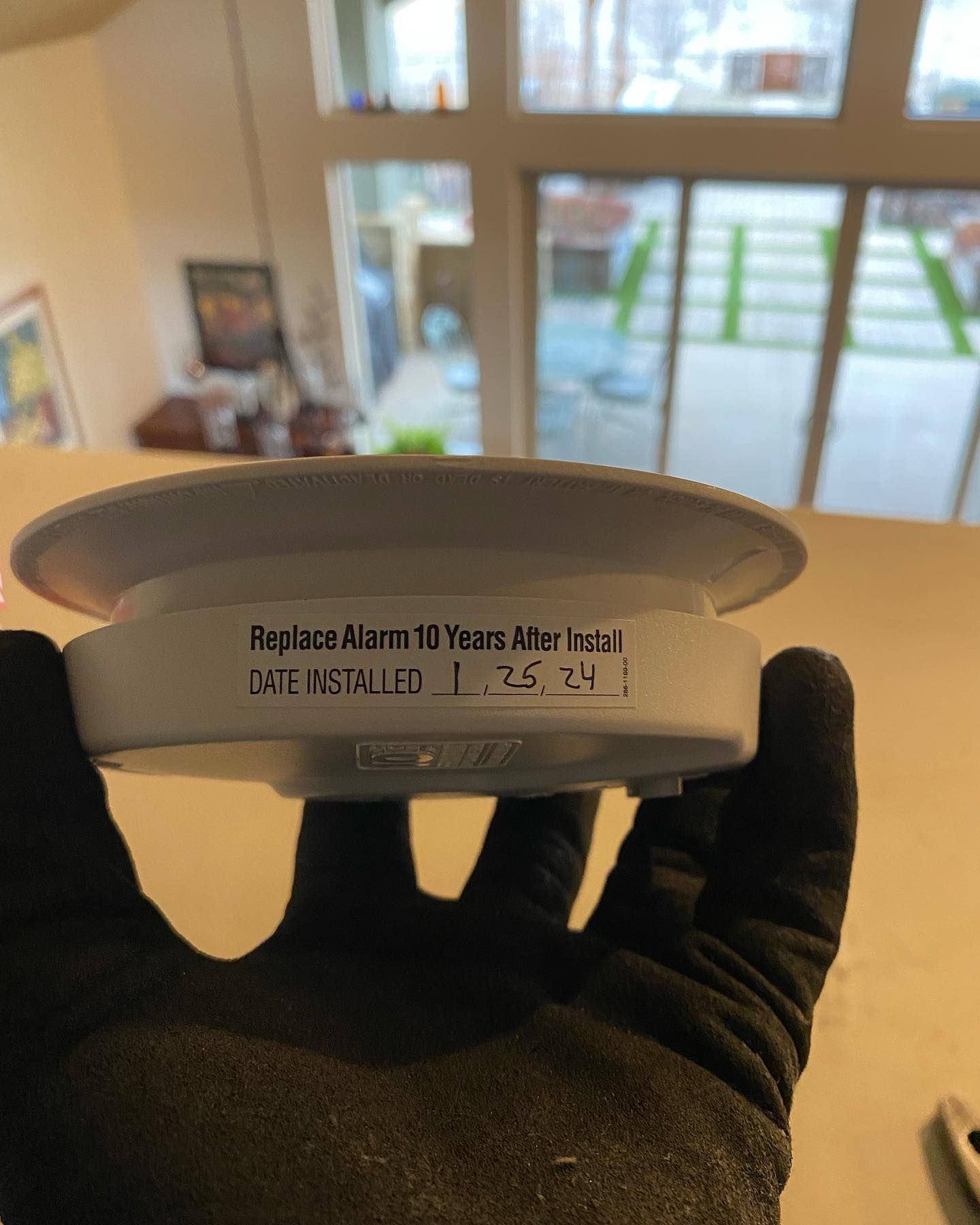 A person is holding a smoke detector in their hand.