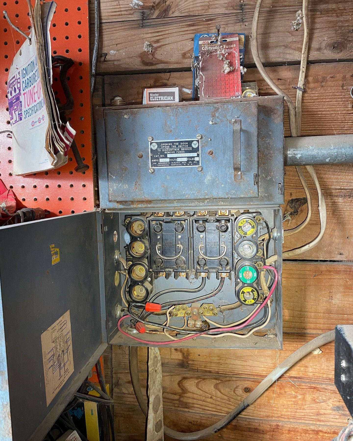 An old electrical box is sitting on a wooden wall.