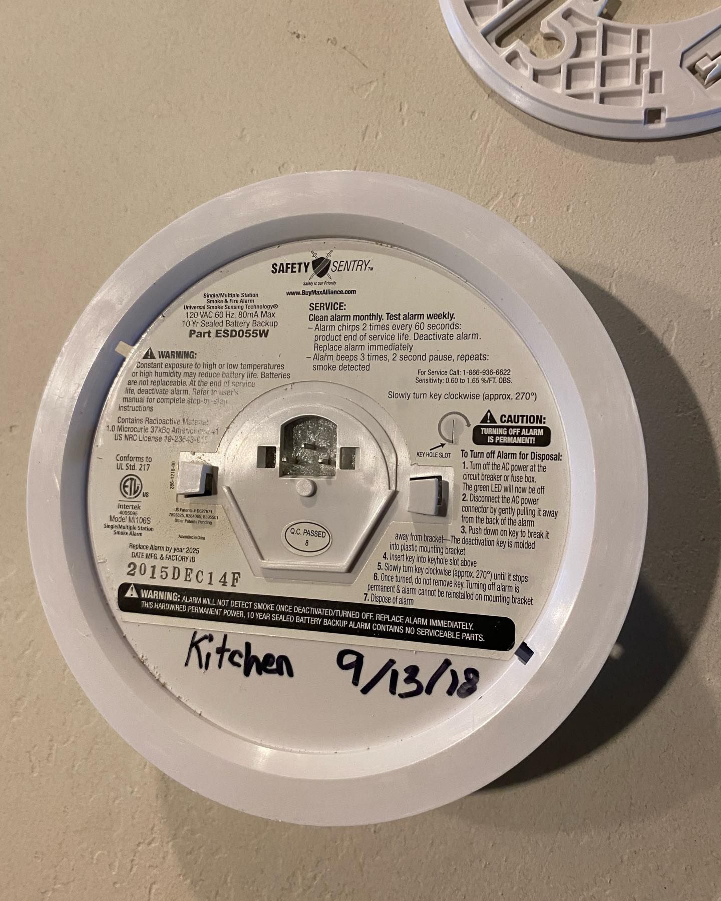 A smoke detector is sitting on a counter with the date 9/13/18 written on it.
