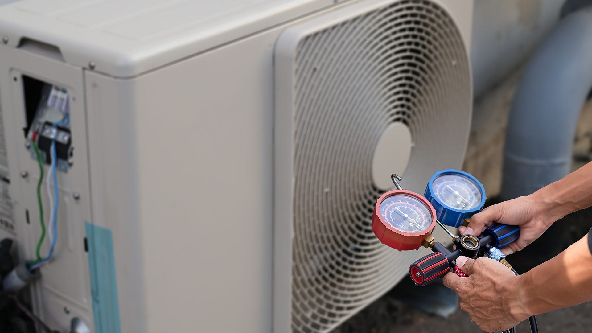 Person using gauges to check an outdoor AC unit.