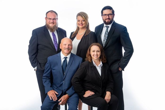 The front door of a house with a porch and plants in front of it.