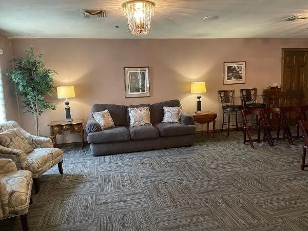 A waiting area with a sofa, chairs, and lamps, in a room with neutral colors.