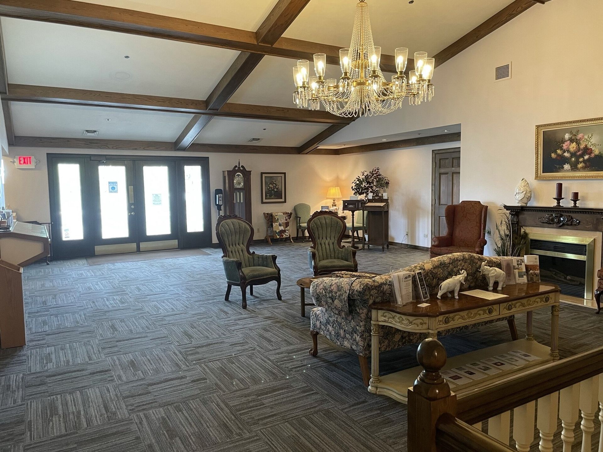 Spacious room with a chandelier, seating area, fireplace, and doors; neutral colors.