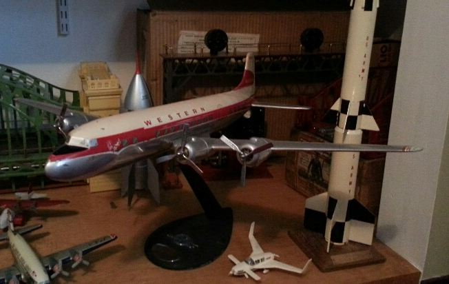 A vintage Western Airlines model airplane displayed on a stand alongside a model rocket and other small aircraft toys.