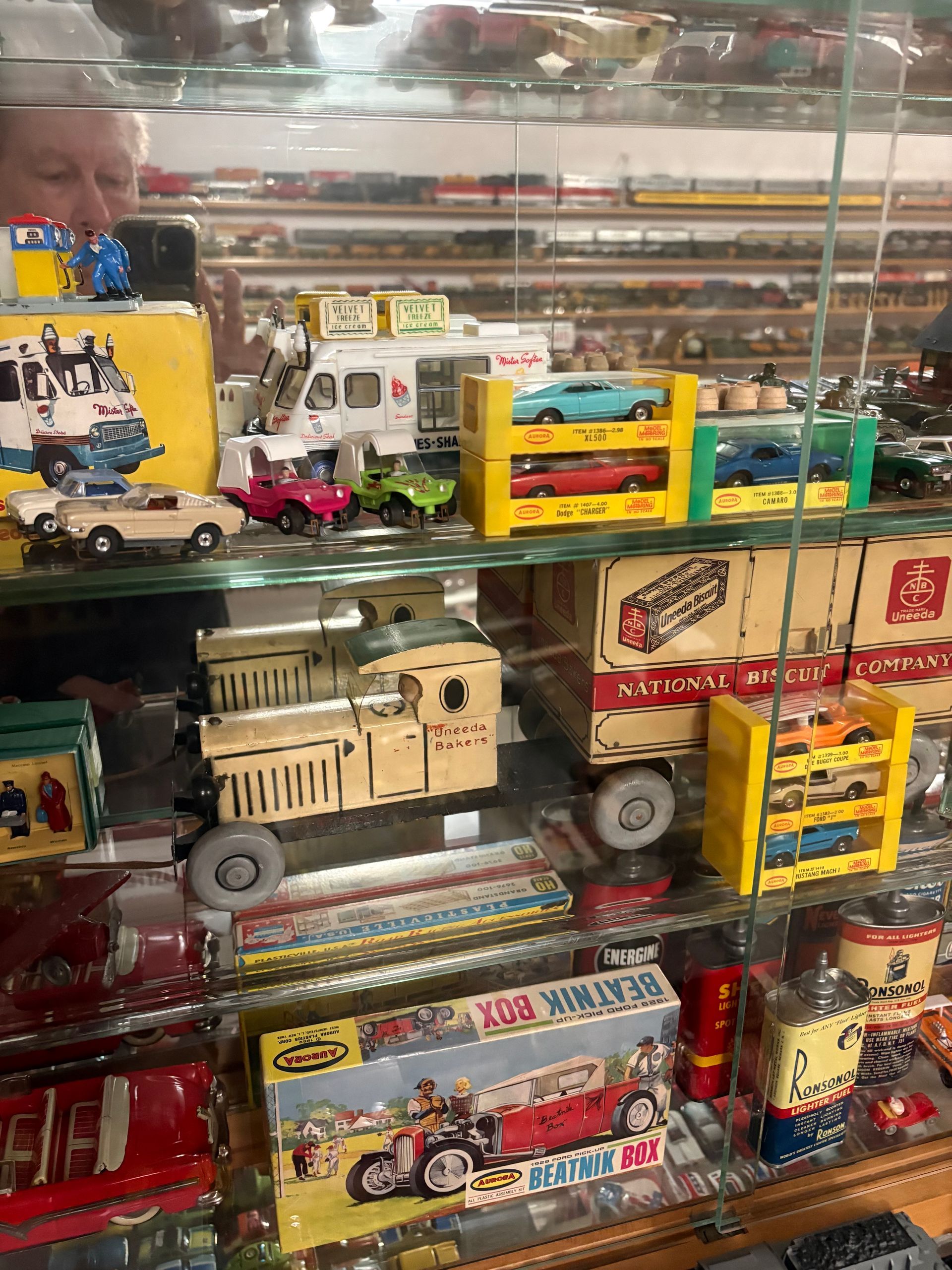 Glass display case filled with toy trucks, cars, and boxed vintage die-cast vehicles.