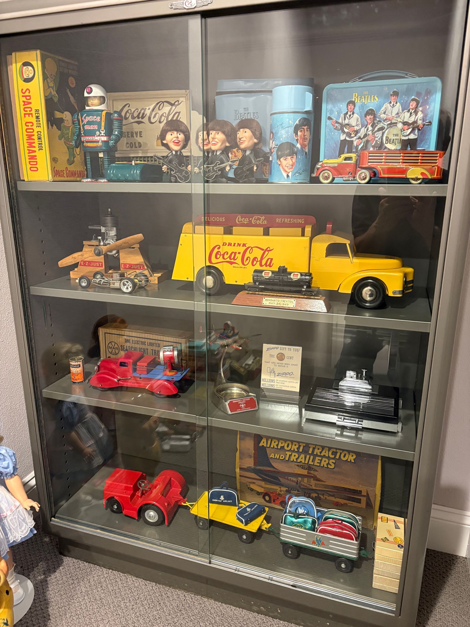 Glass display cabinet filled with colorful toy trucks, cars, and collectible models on shelves