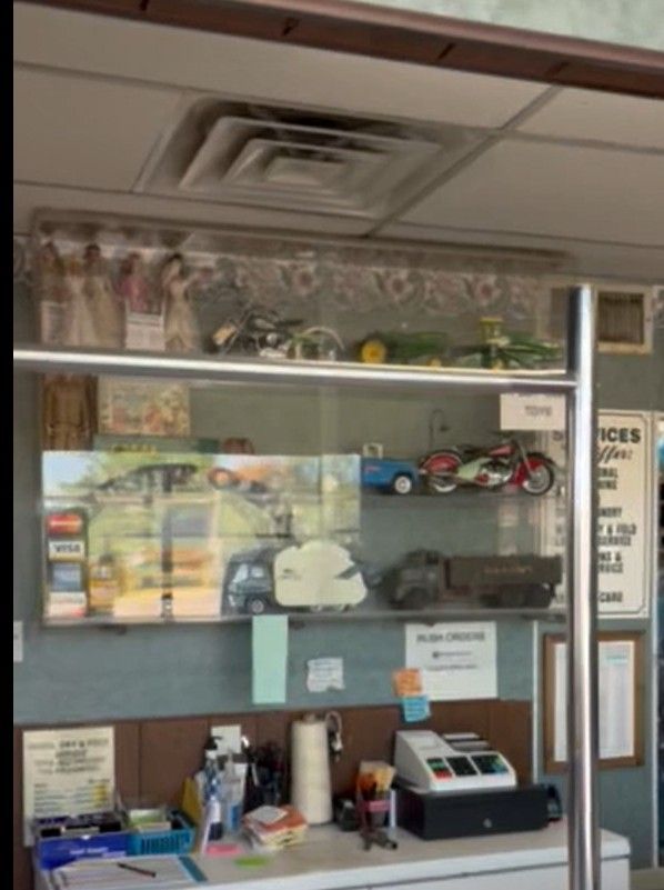 Office reception counter with shelves of model cars and small items behind glass display cases