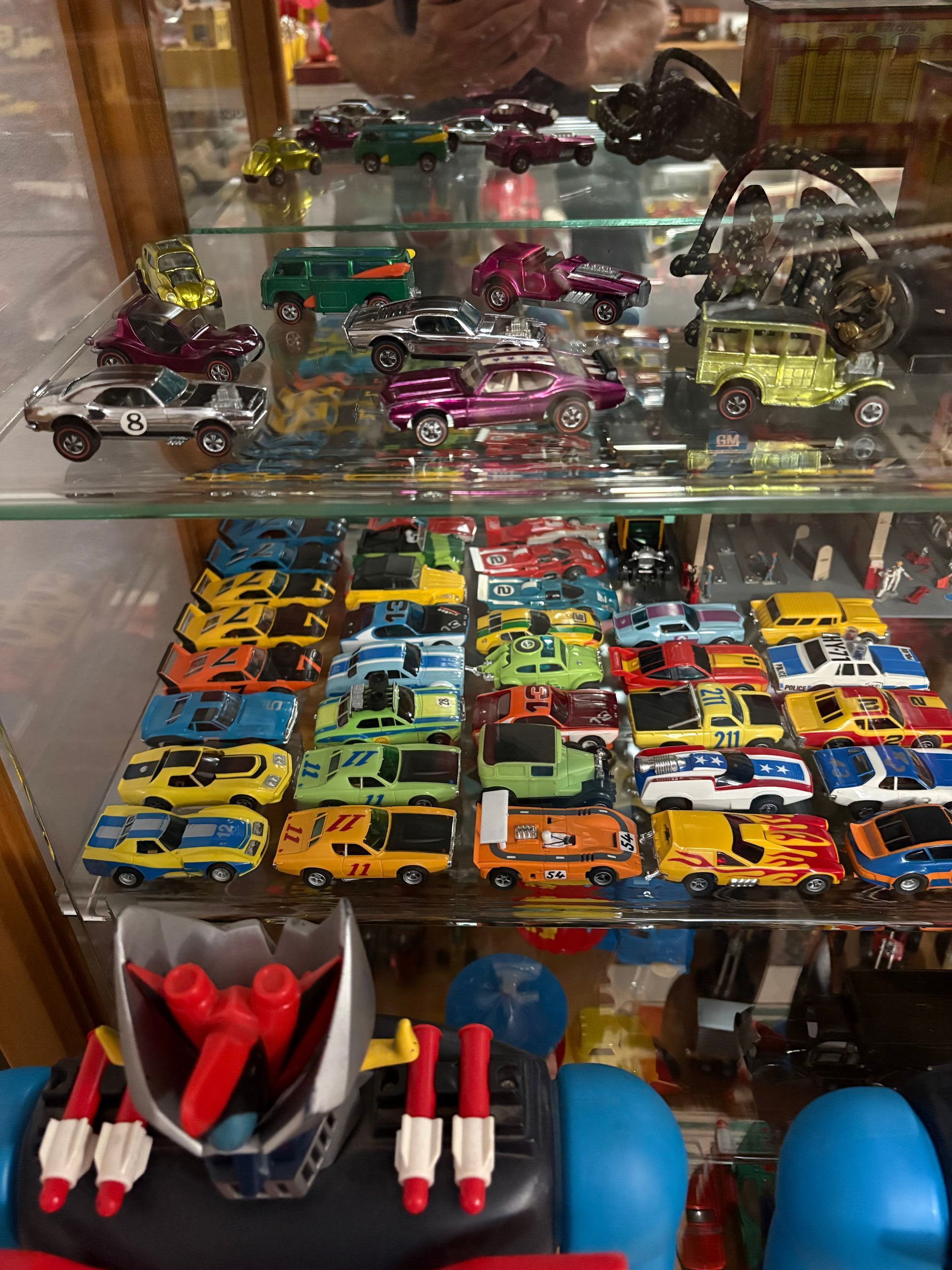 Glass display case filled with colorful toy cars, trucks, and rockets on shelves