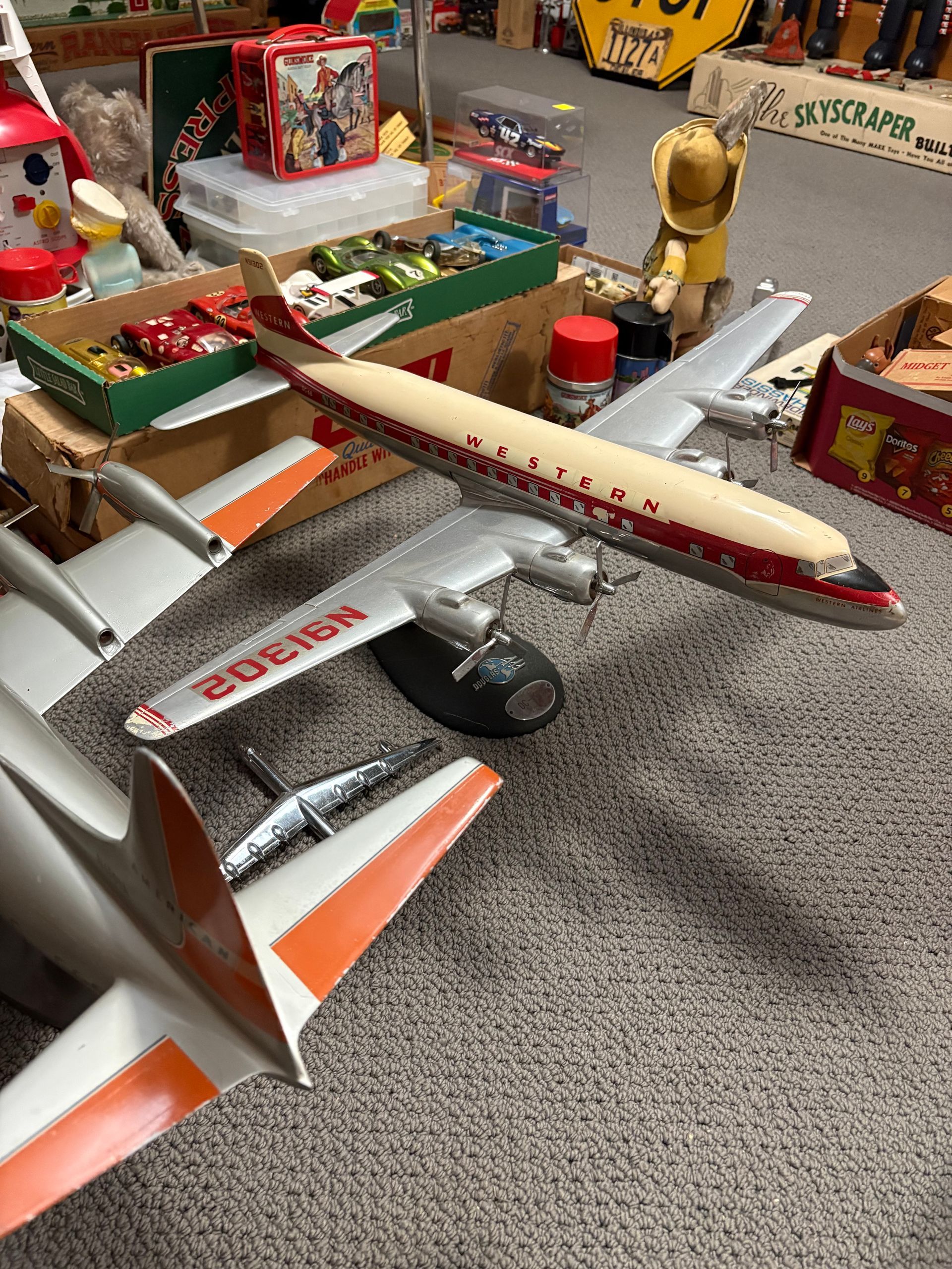Toy airplanes displayed on a carpeted floor, including a cream-and-red plane in the foreground.