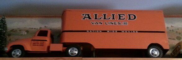 A vintage orange Allied Van Lines toy semi-truck displayed on a shelf against a landscape wallpaper background.