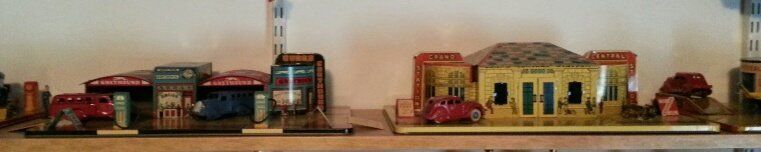 Vintage model toy dioramas featuring gas station and building structures with miniature cars displayed on a shelf.