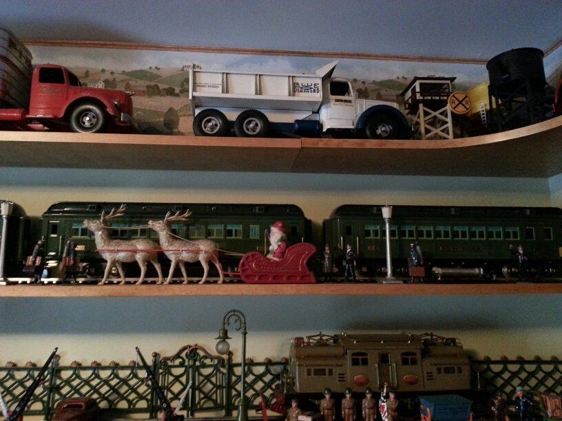 Shelves displaying vintage toy trucks, a model train with a deer-drawn sleigh, and miniature soldiers with a train engine.