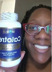 Person holding a bottle of Calotren weight loss formula, smiling with eyeglasses.