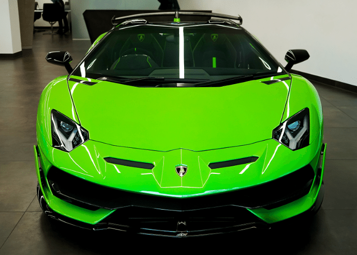 A green lamborghini aventador is parked in a showroom.