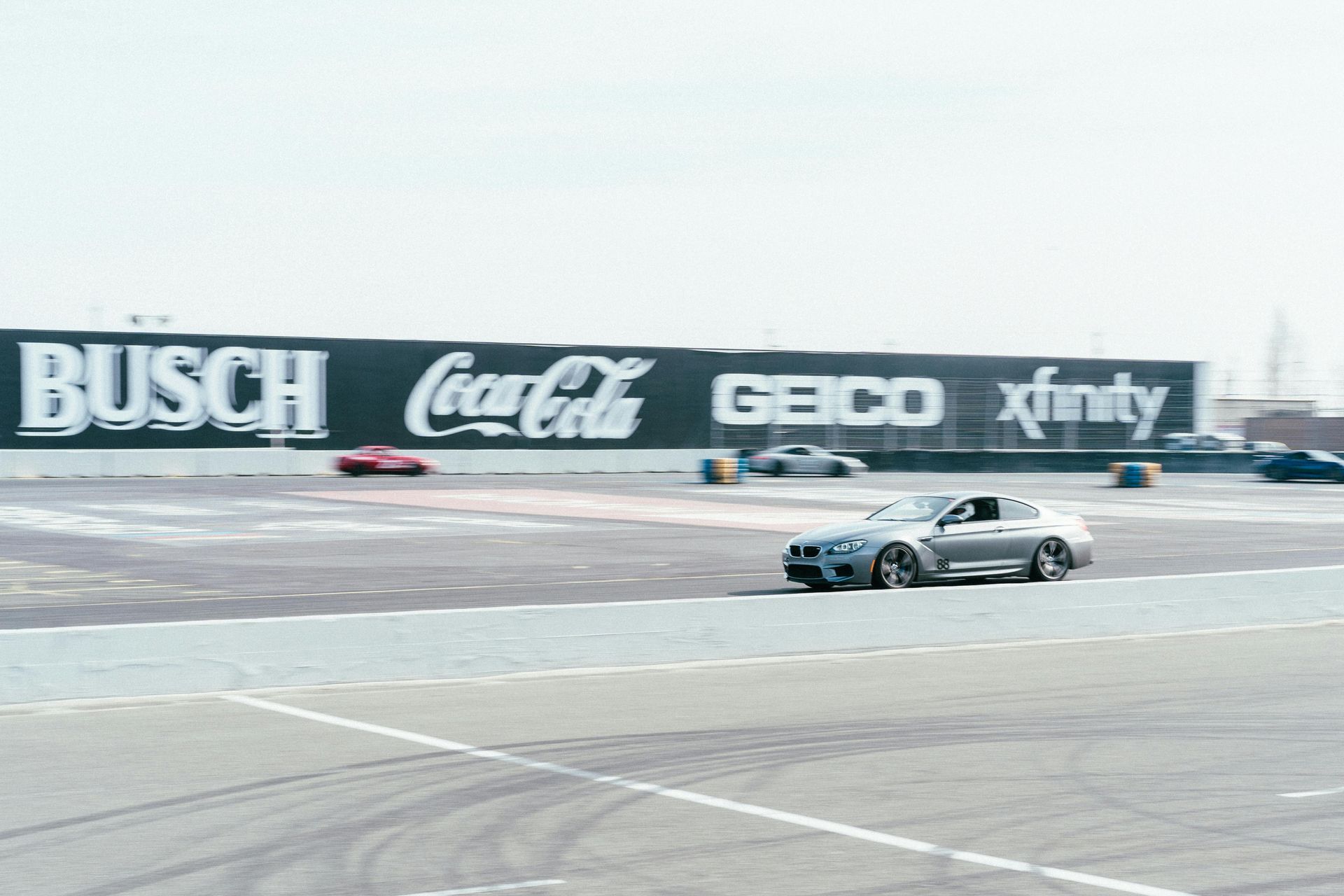 A car is driving in front of a busch coca cola geico and xfinity sign