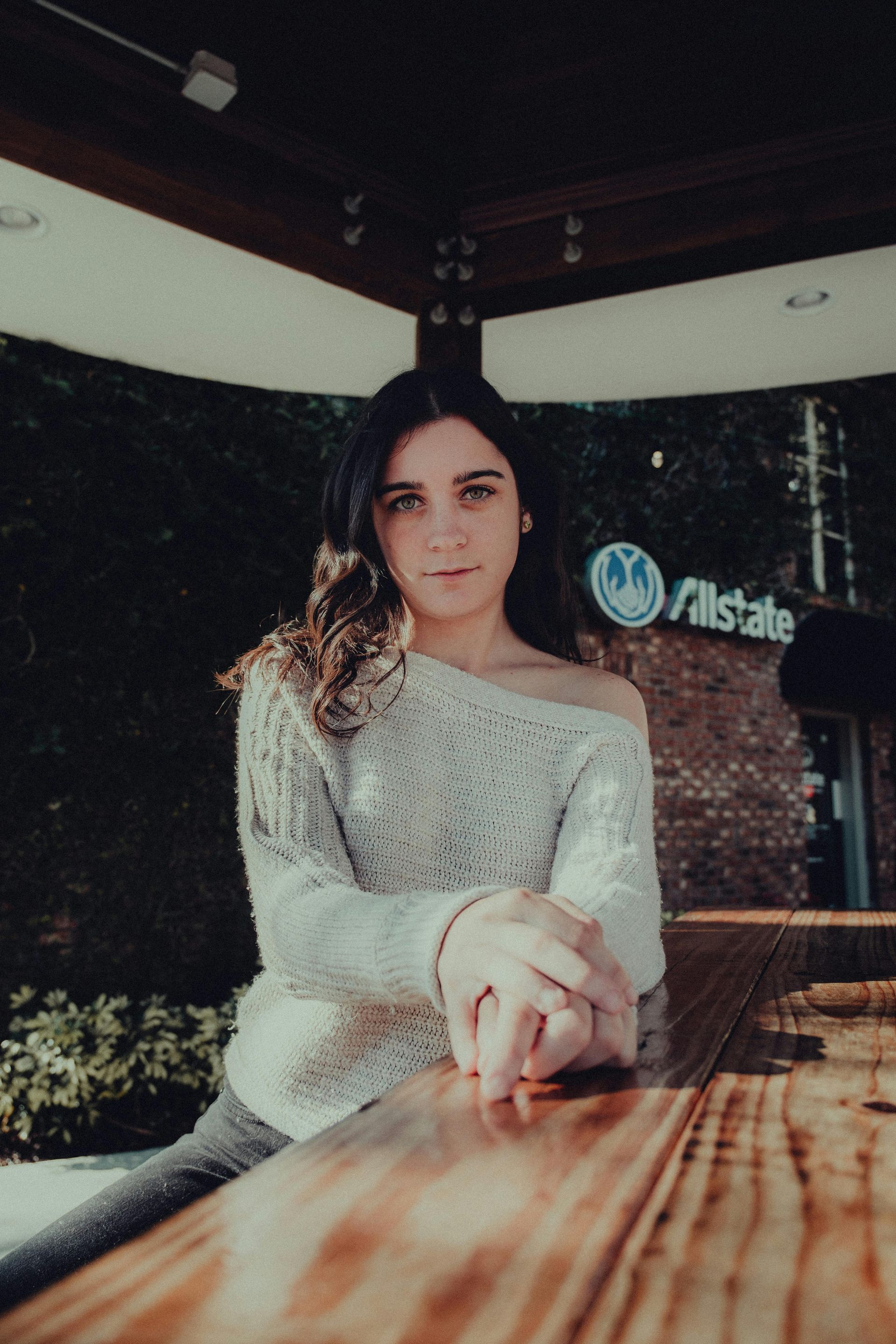 A woman is sitting at a table in front of an allstate building.