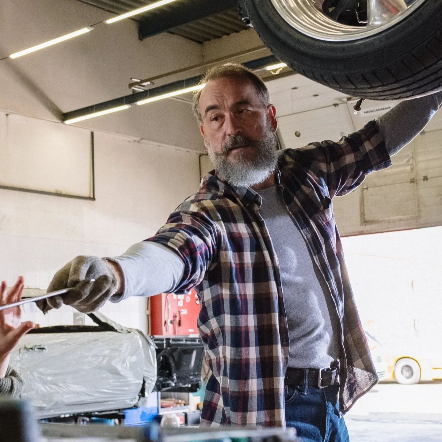 A man with a beard is working on a car in a garage.