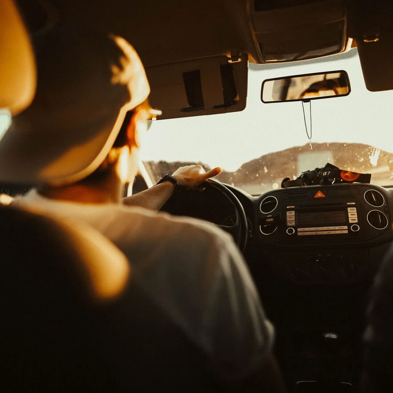 A man in a hat is driving a car