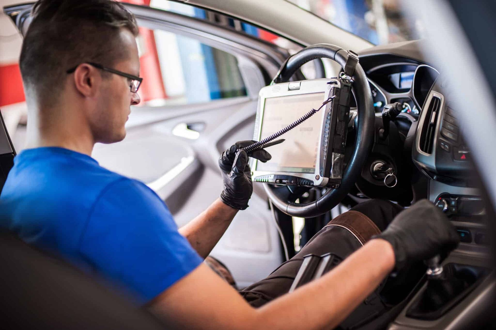 A man is sitting in a car using a tablet computer.