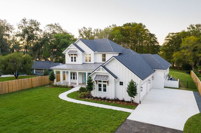 An aerial view of a white house with a blue roof and a driveway.