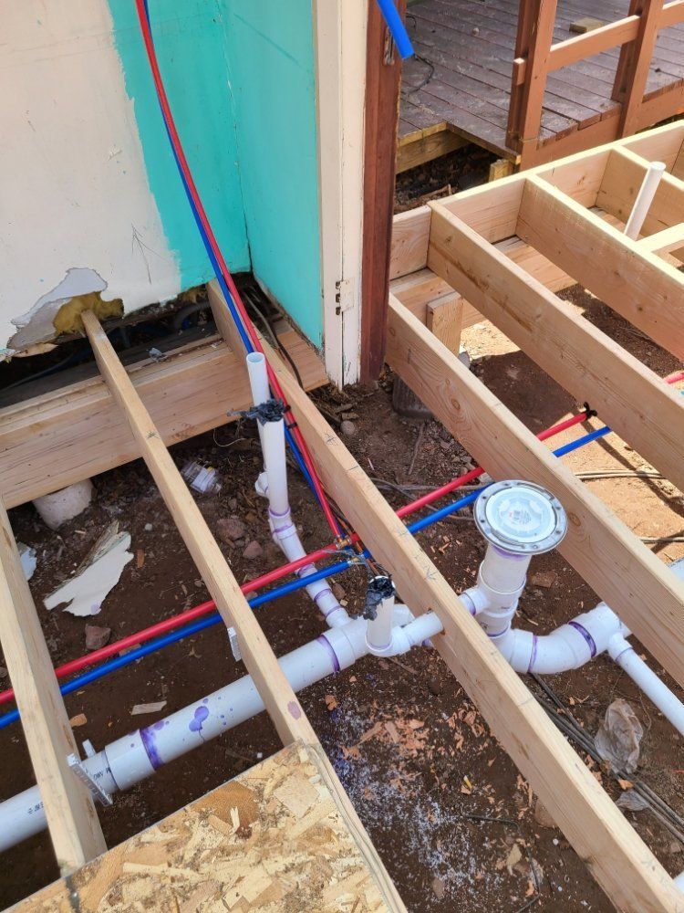 A bunch of pipes are under a wooden floor